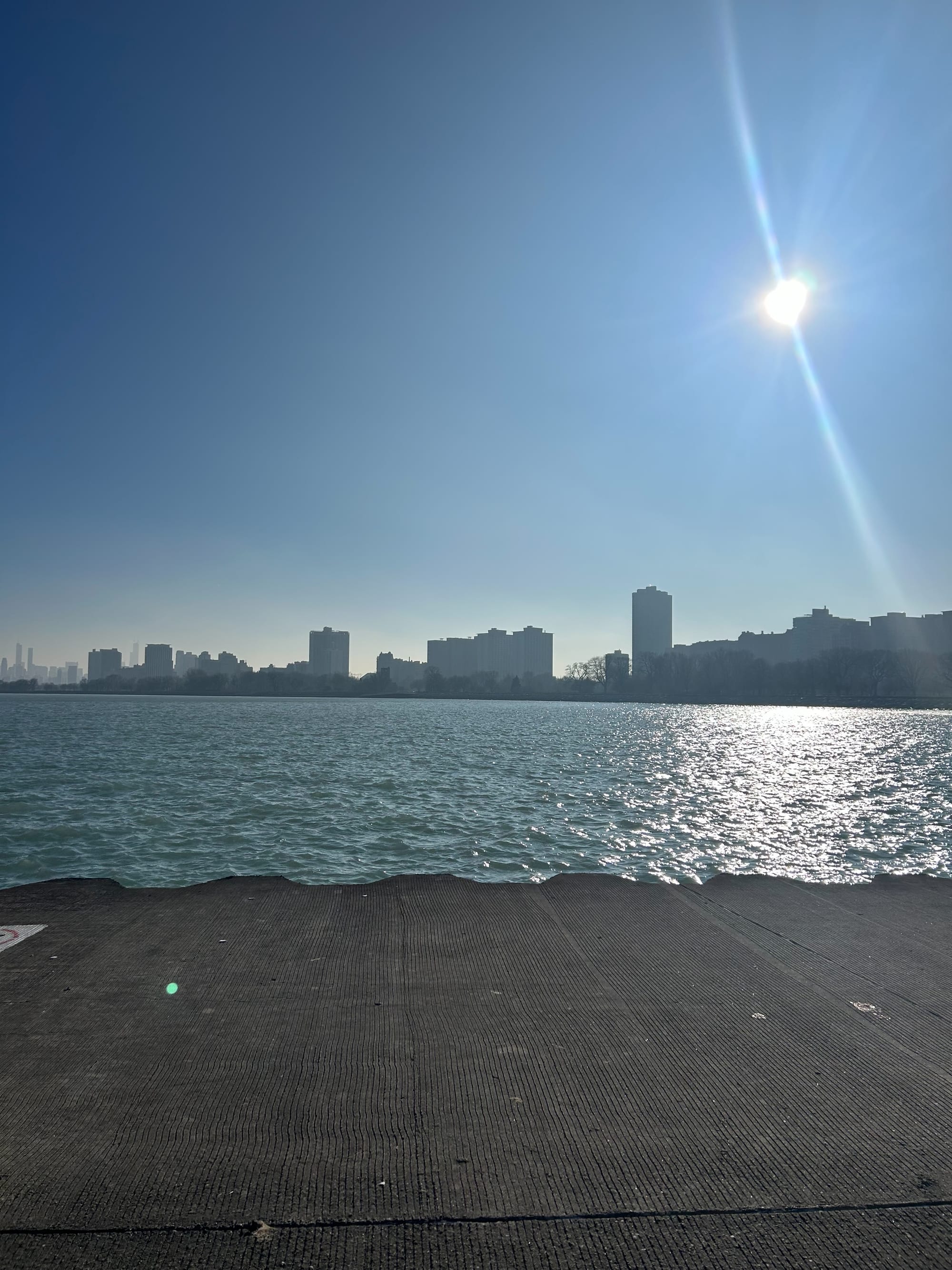 Sunny day, blue sky, concrete platform by the lake. Skyline of Chicag